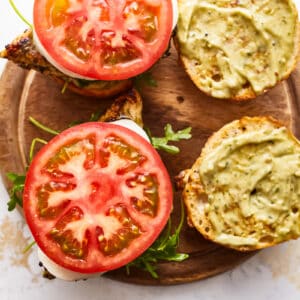 open pesto chicken sandwiches on a cutting board.