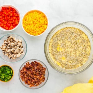 seasoned eggs in a glass bowl next to toppings in glass bowls.