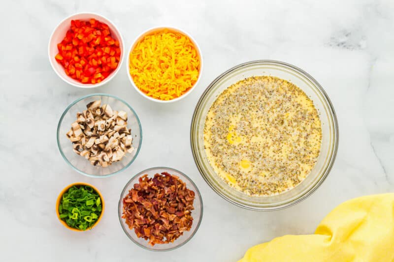 seasoned eggs in a glass bowl next to toppings in glass bowls.
