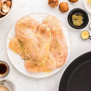 seasoned chicken breasts on a white plate.