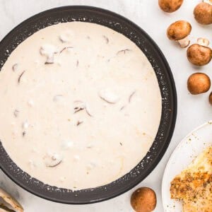 creamy white sauce with mushrooms in a skillet.