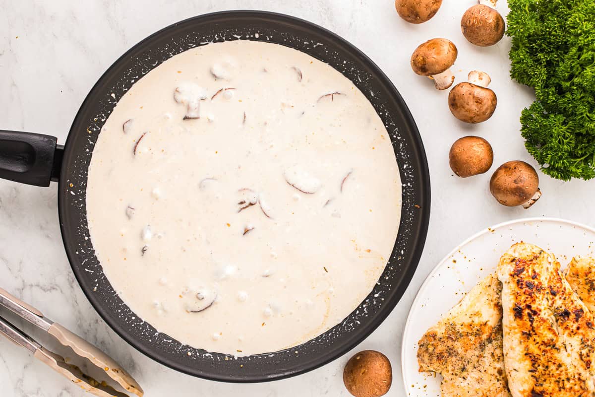 creamy white sauce with mushrooms in a skillet.