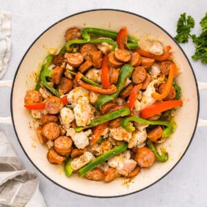 sauteed veggies, chicken, and sausage in a pan.