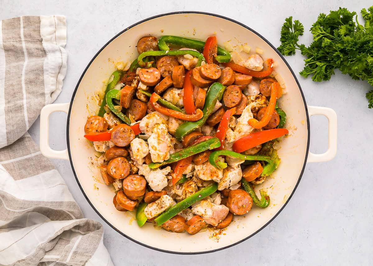 sauteed veggies, chicken, and sausage in a pan.