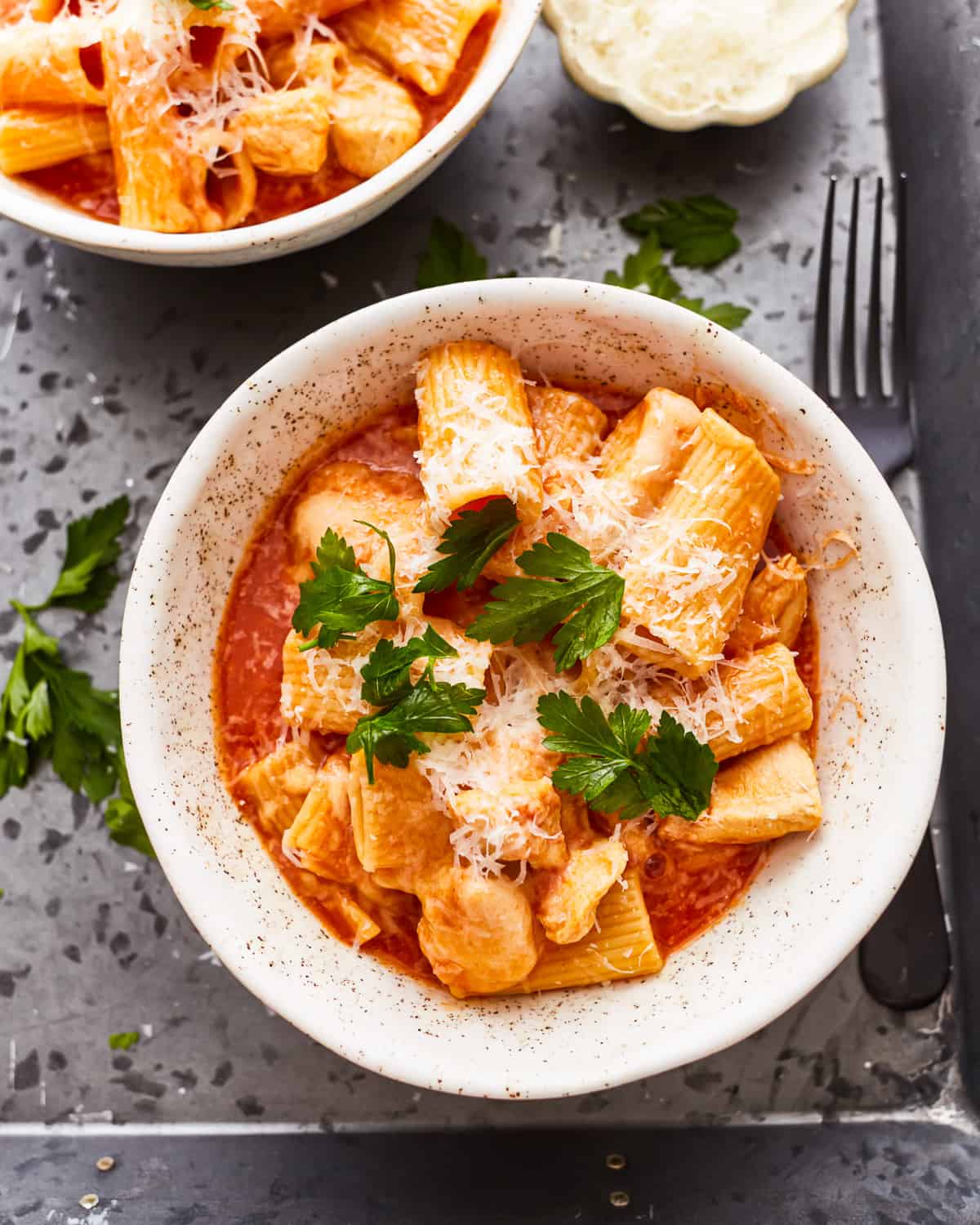 overhead view of a serving of instant pot chicken parmesan pasta in a white bowl.