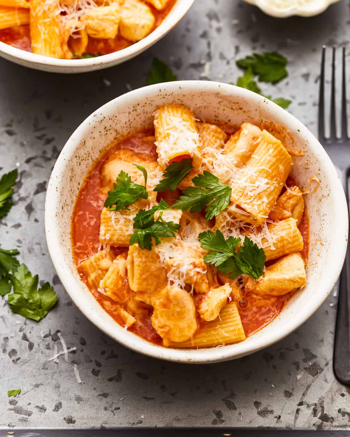 two-thirds view of a serving of instant pot chicken parmesan pasta in a white bowl.