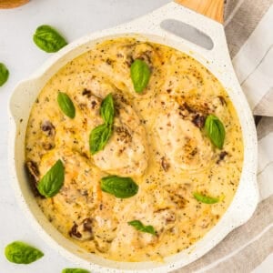 overhead view of marry me chicken topped with fresh basil leaves in a white pan.
