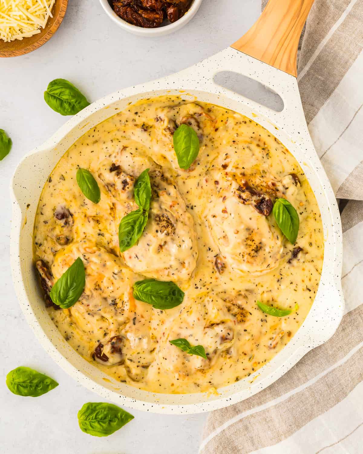 overhead view of marry me chicken topped with fresh basil leaves in a white pan.