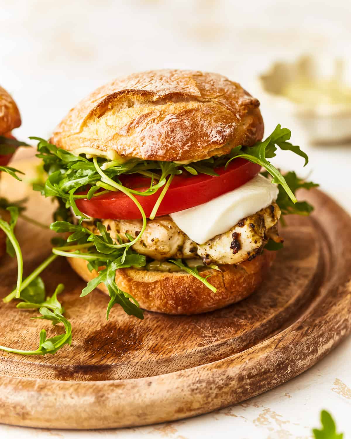 a pesto chicken sandwich on a wooden cutting board.