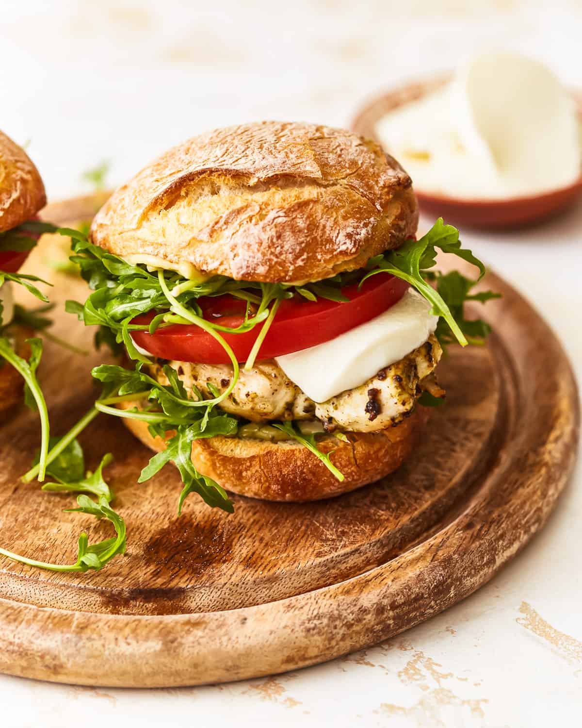 a pesto chicken sandwich on a wooden cutting board.