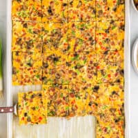 a spatula lifting a serving of sheet pan eggs from a pan.