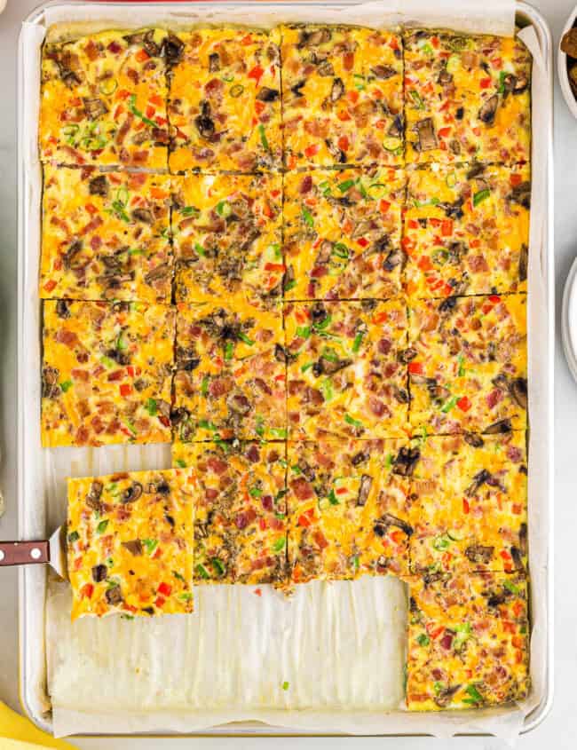 a spatula lifting a serving of sheet pan eggs from a pan.