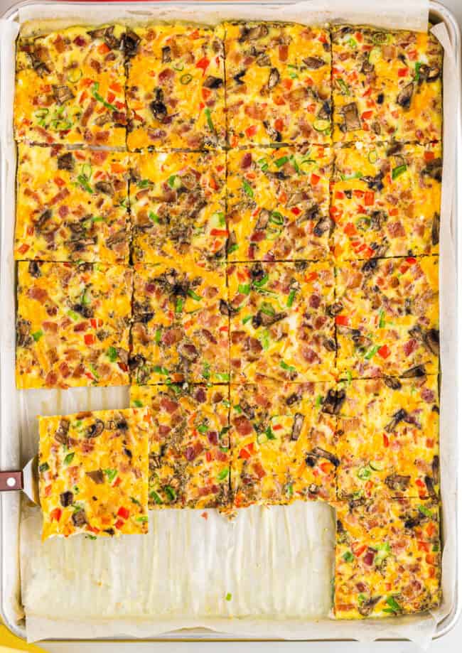 a spatula lifting a serving of sheet pan eggs from a pan.