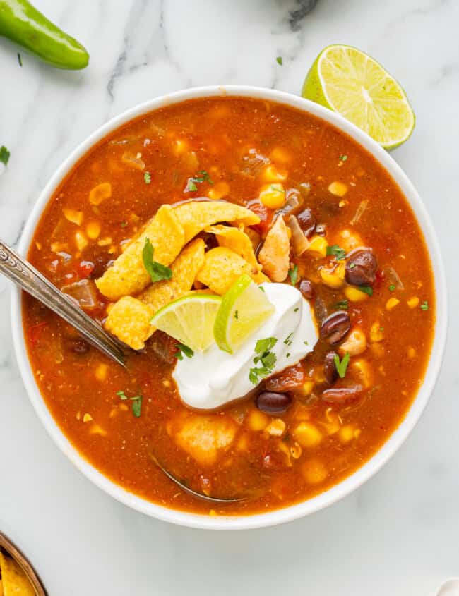 overhead view of a serving of southwest chicken soup in a bowl with a spoon.