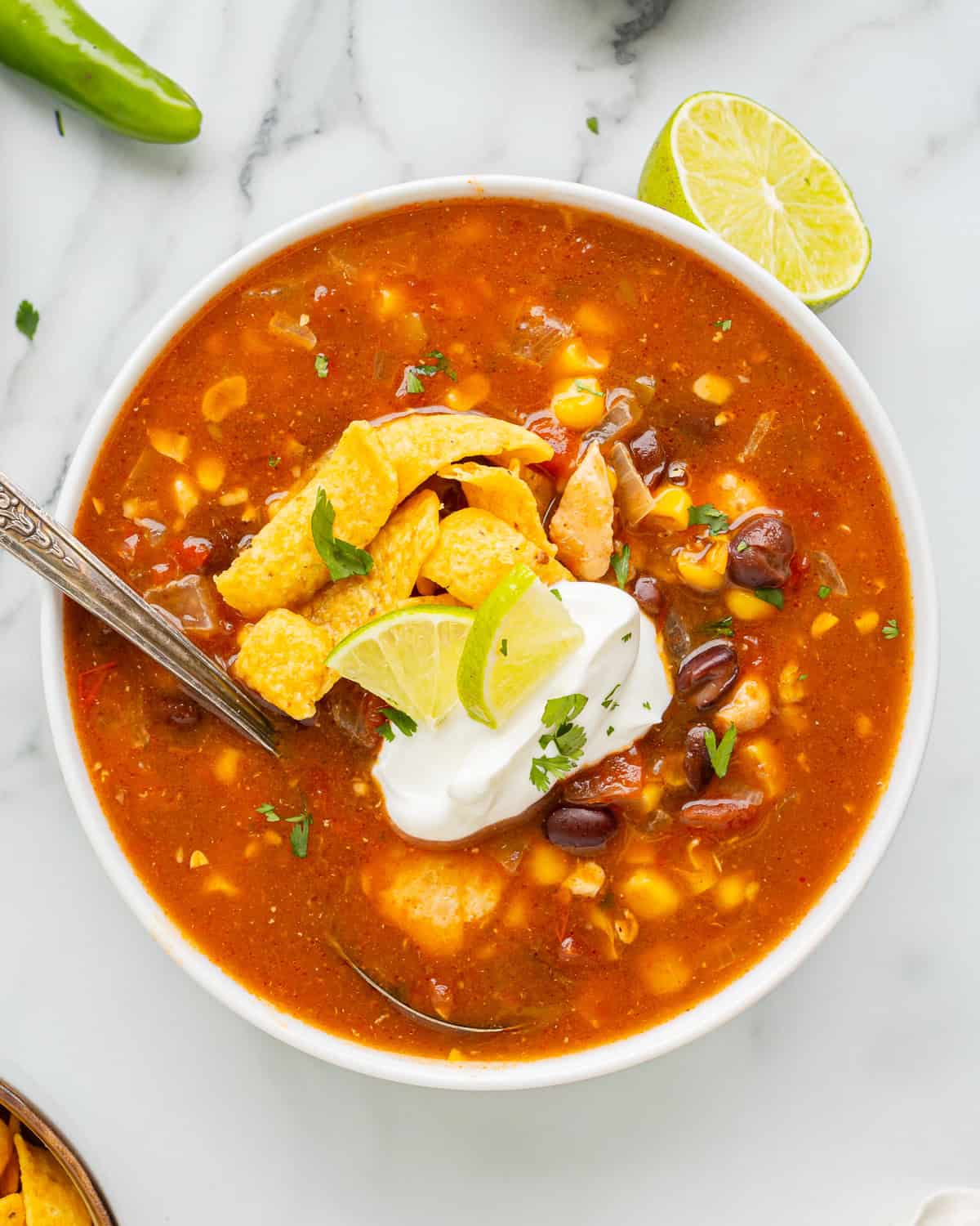 overhead view of a serving of southwest chicken soup in a bowl with a spoon.