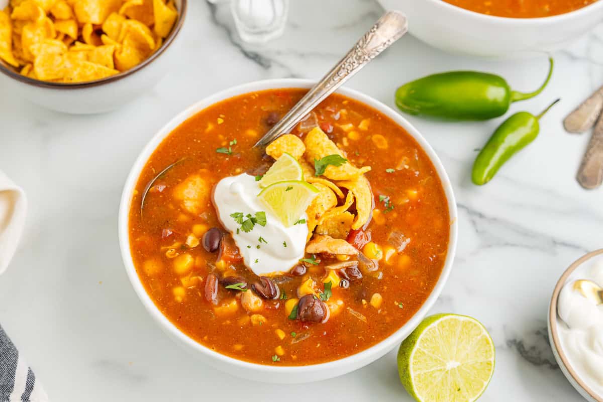 three-quarters view of a serving of southwest chicken soup in a bowl with a spoon.