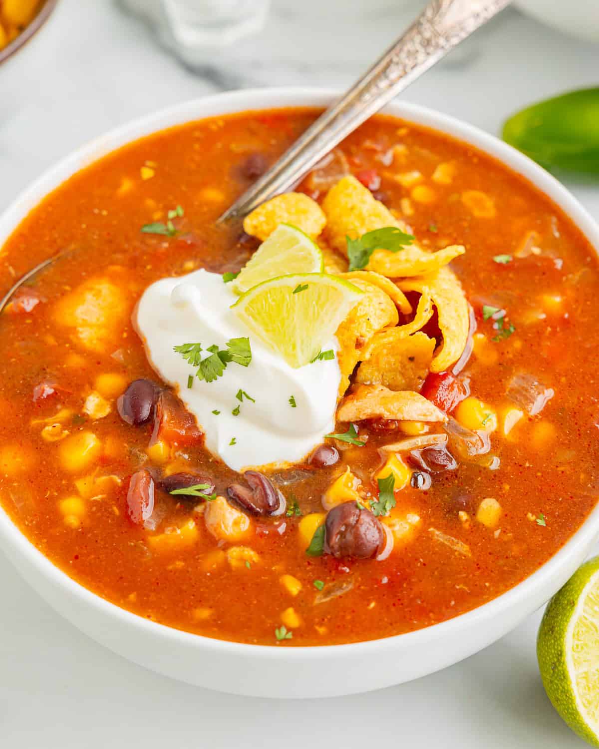 close up view of a serving of southwest chicken soup in a bowl with a spoon.