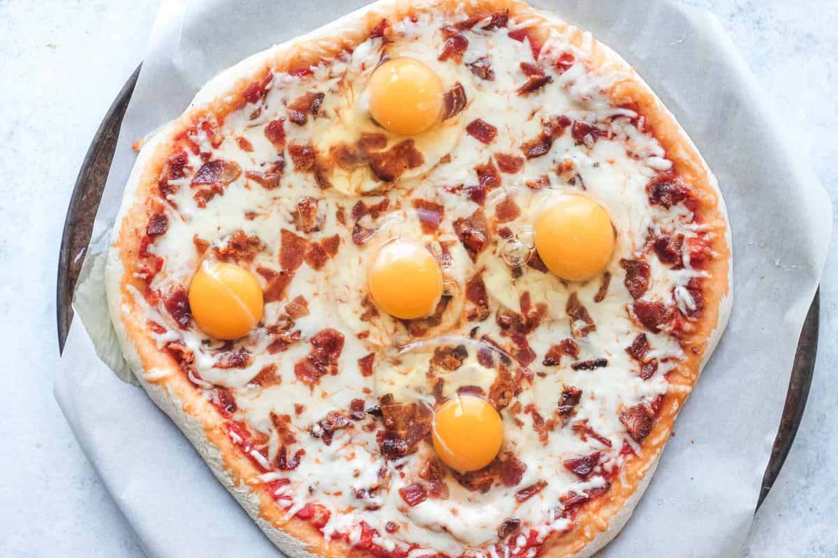 a breakfast pizza with eggs and bacon on top.