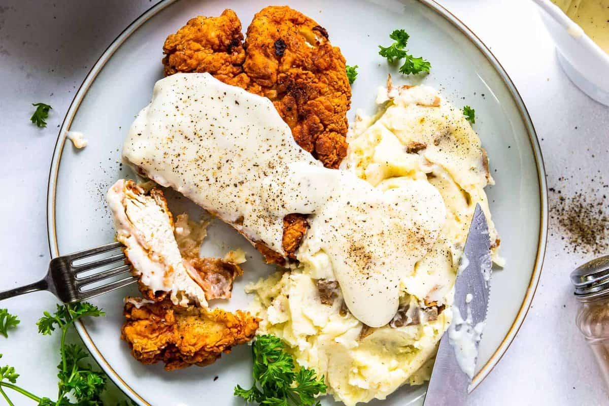plate of chicken fried chicken with gravy next to mashed potatoes