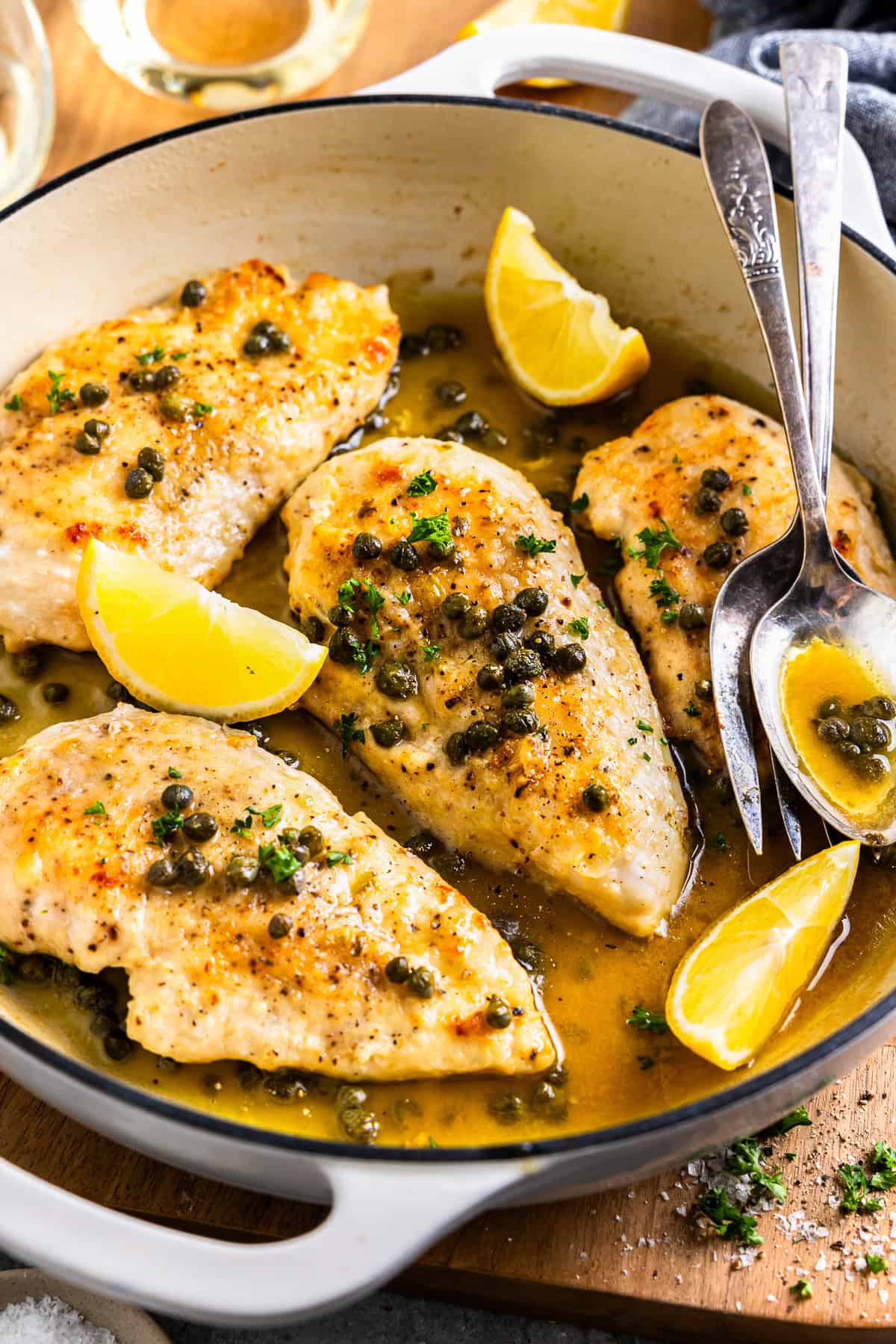 chicken piccata with lemon and spoon in white skillet