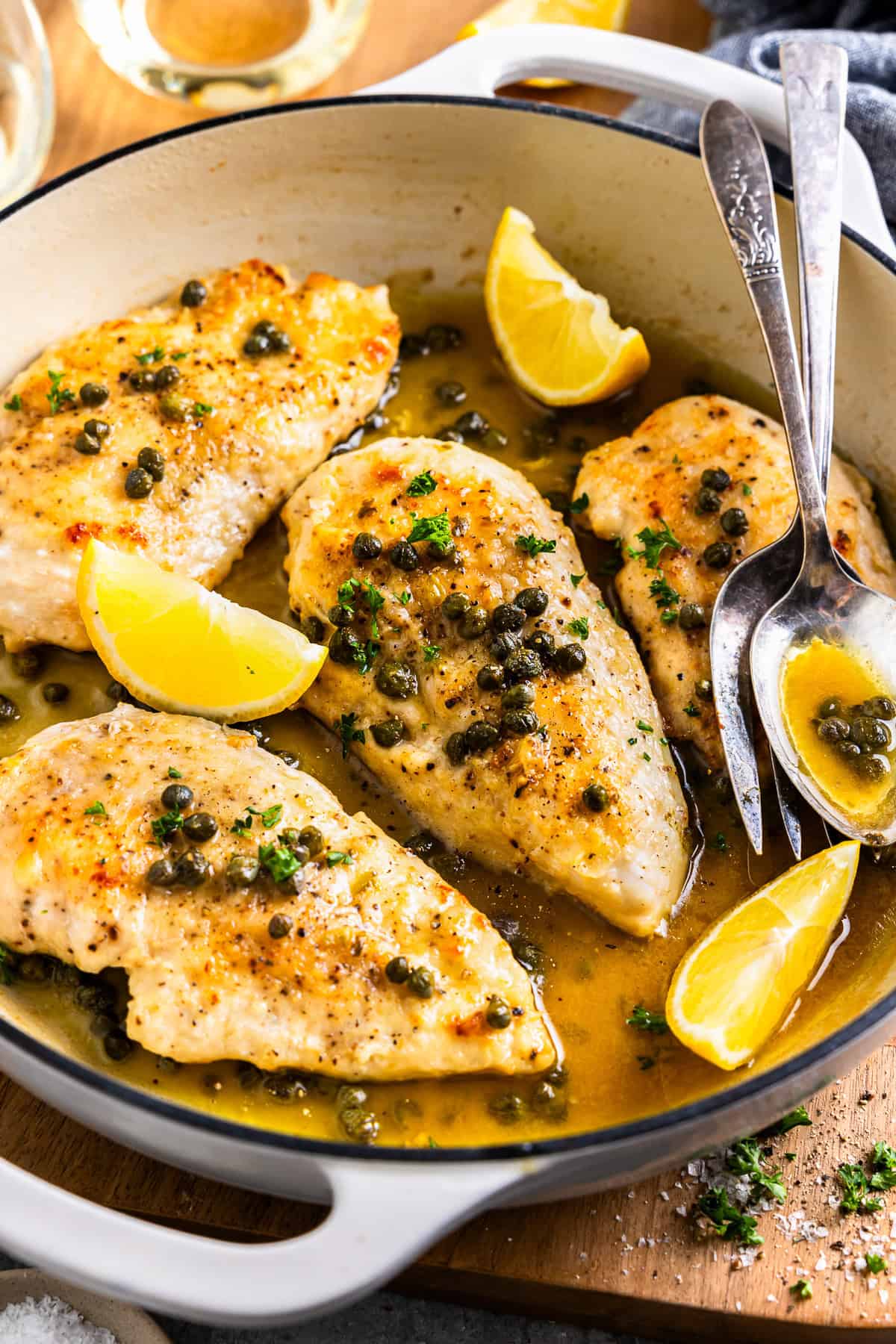 chicken piccata with lemon wedges in a white skillet