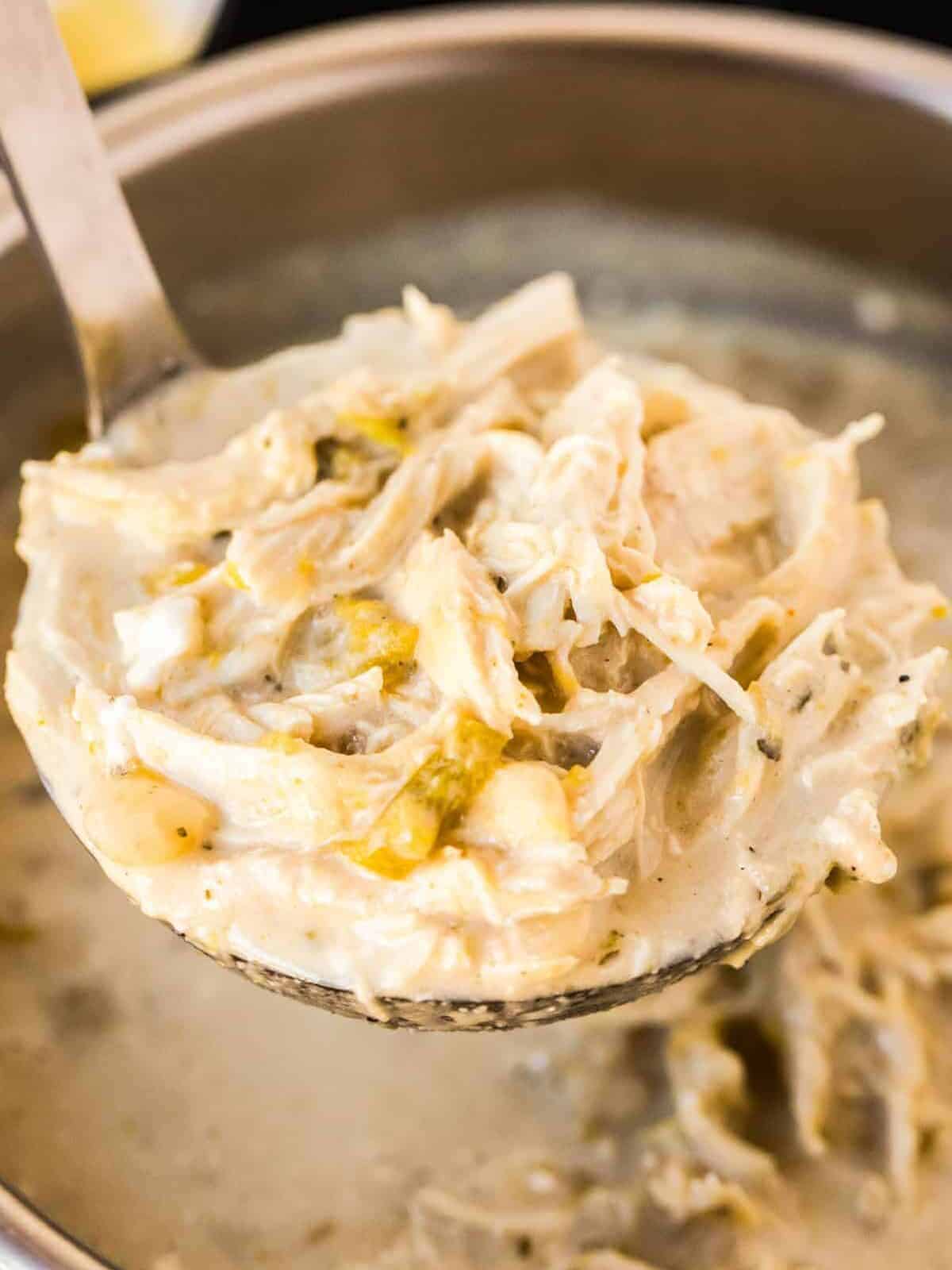 dipping spoon of white chicken chili out of instant pot