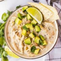 bowl of instant pot white chicken chili garnished with avocado and chips