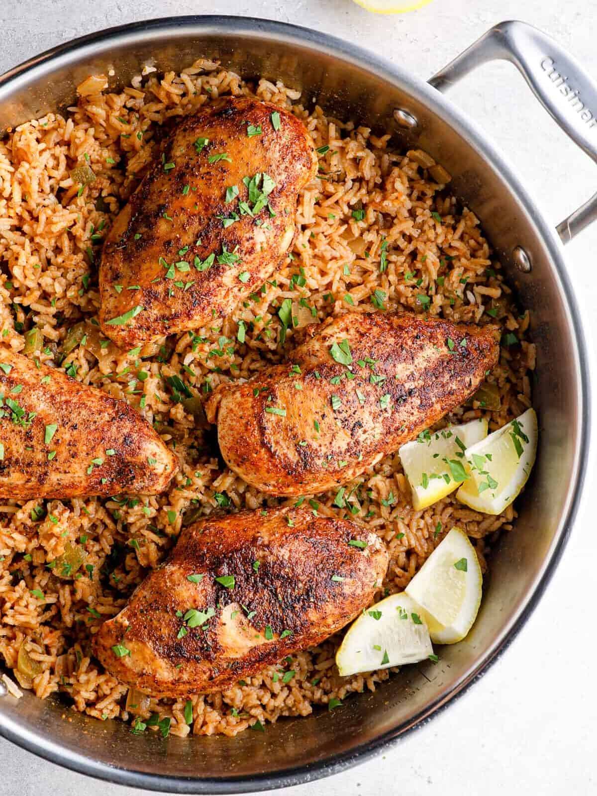 overhead image of cajun chicken breasts on top of rice in a skillet