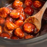 bbq chicken meatballs in a crockpot with a wood spoon