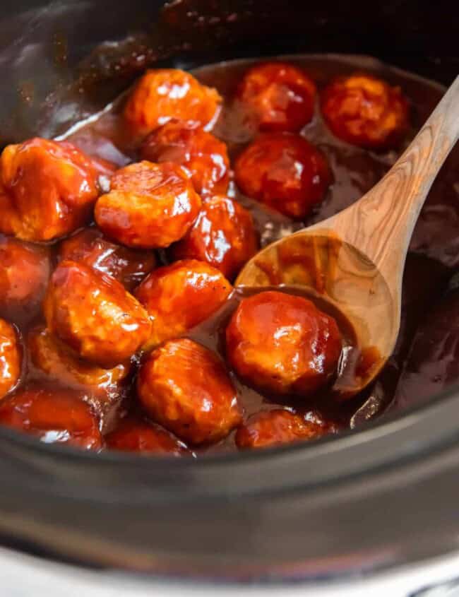 bbq chicken meatballs in a crockpot with a wood spoon