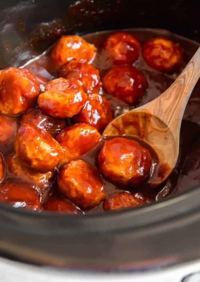 bbq chicken meatballs in a crockpot with a wood spoon