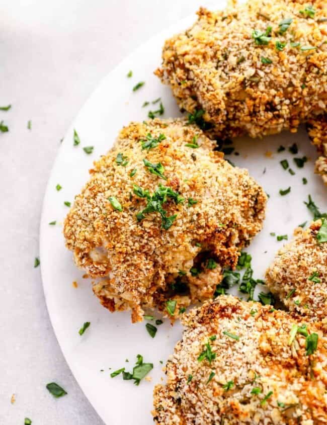 deviled chicken thighs on a white plate with parsley.