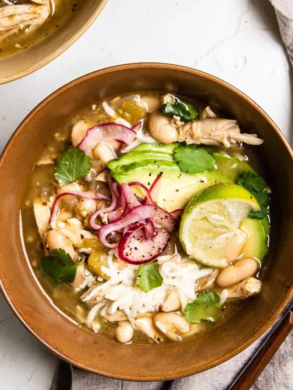 overhead image of green chile chicken soup in a tan bowl