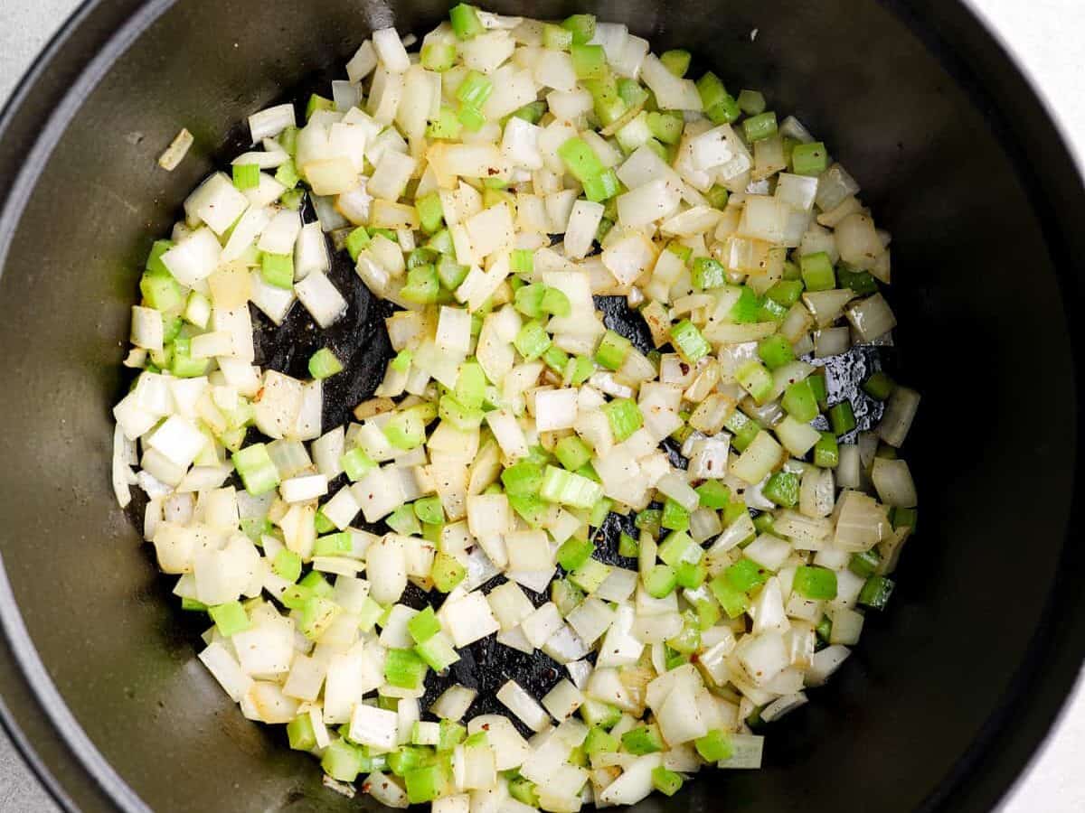 Diced celery and onion cooking in a pot.