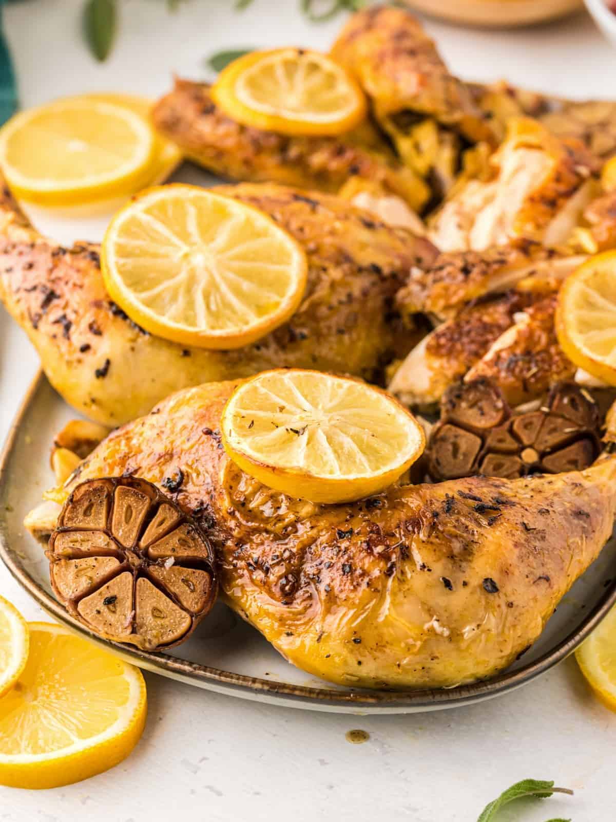 lemon garlic spatchcock chicken on a plate with lemon slices