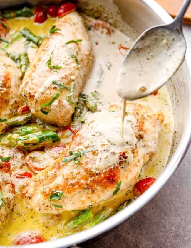 spoon drizzling sauce onto chicken breast in a skillet