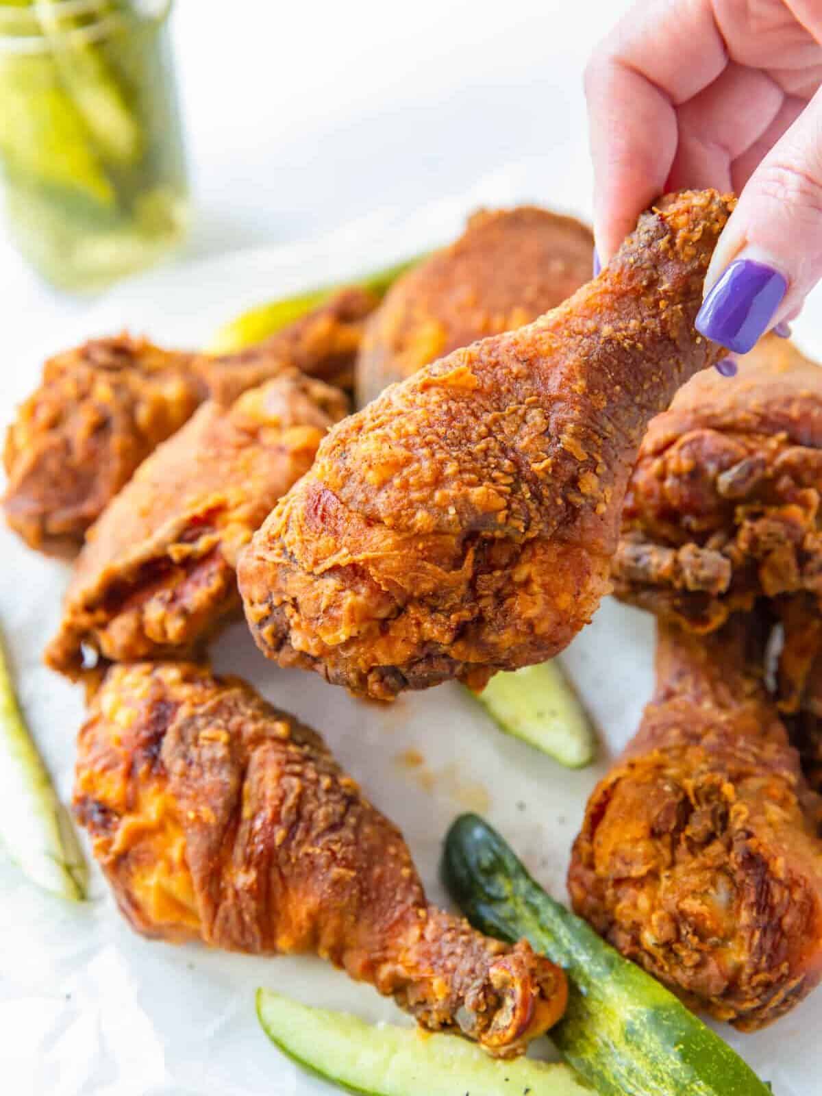 hand holding a pickle brined fried chicken drumstick