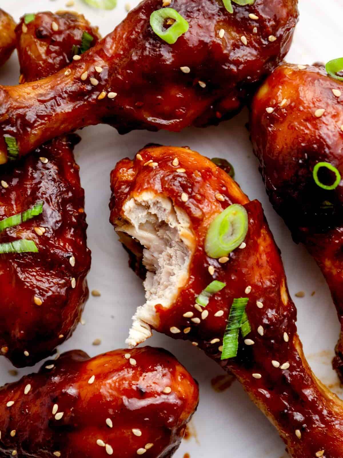 baked teriyaki chicken drumsticks, one has a bite taken out.