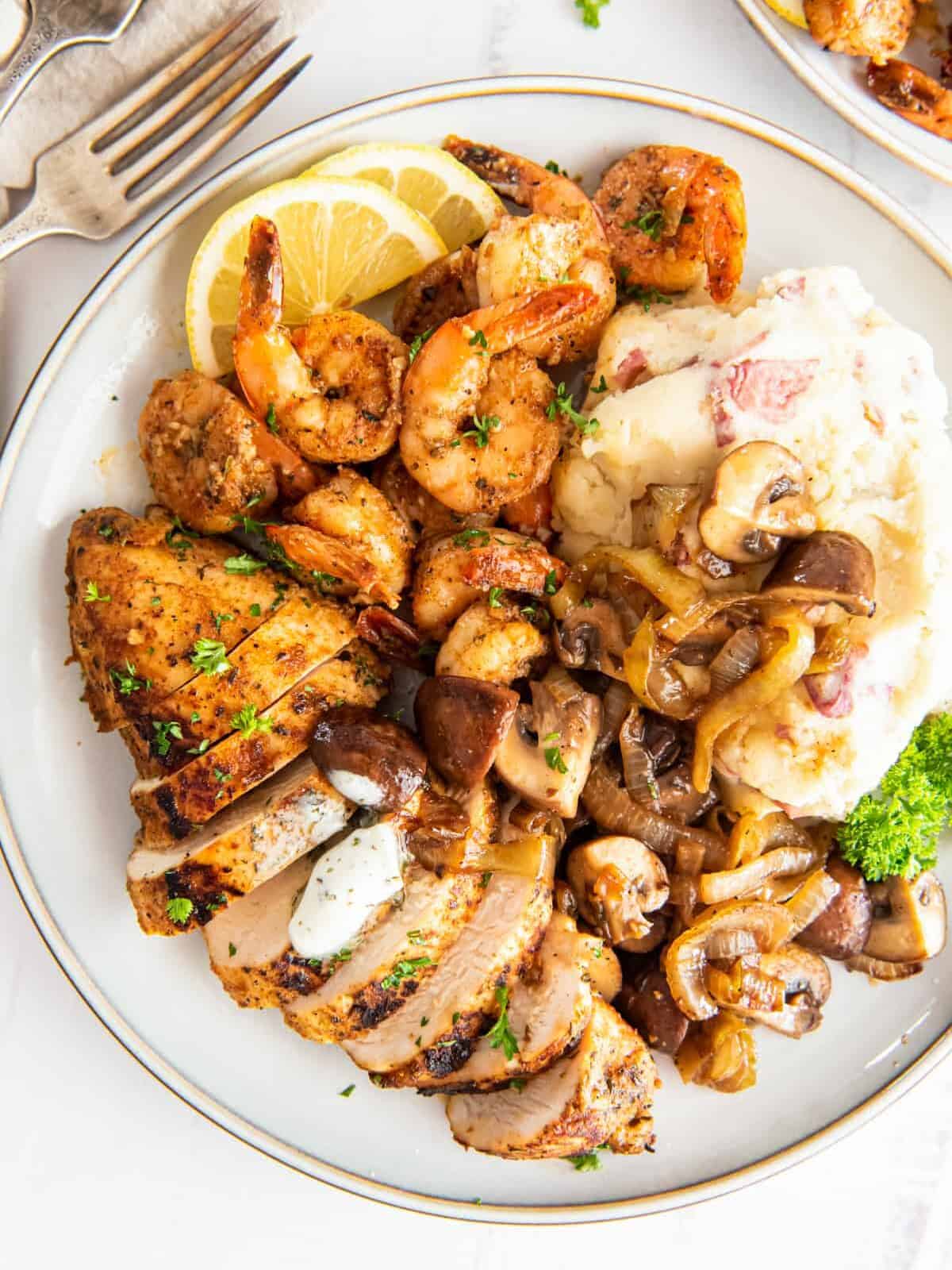 applebees bourbon street chicken and shrimp with mashed potatoes and mushrooms on a white plate.
