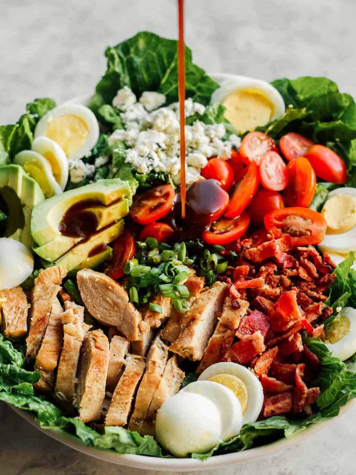 pouring dressing on chicken cobb salad