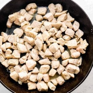 chicken chunks cooking in cast iron skillet