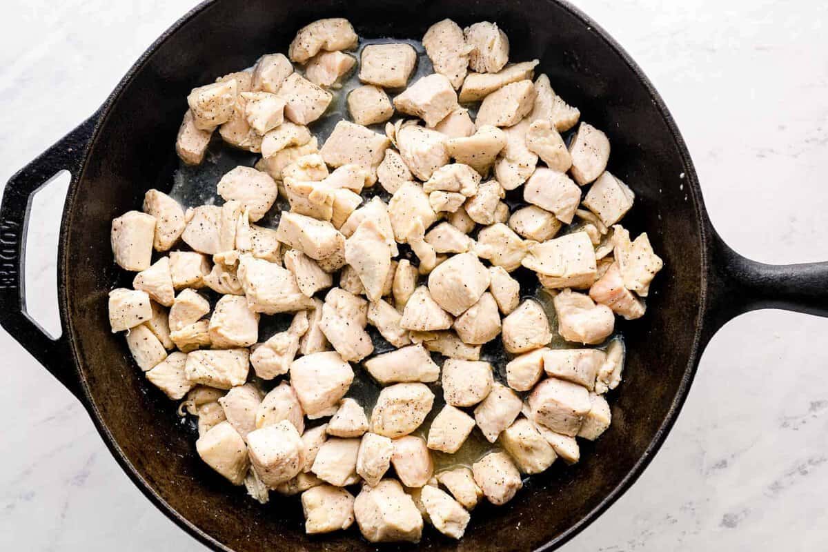 chicken chunks cooking in cast iron skillet