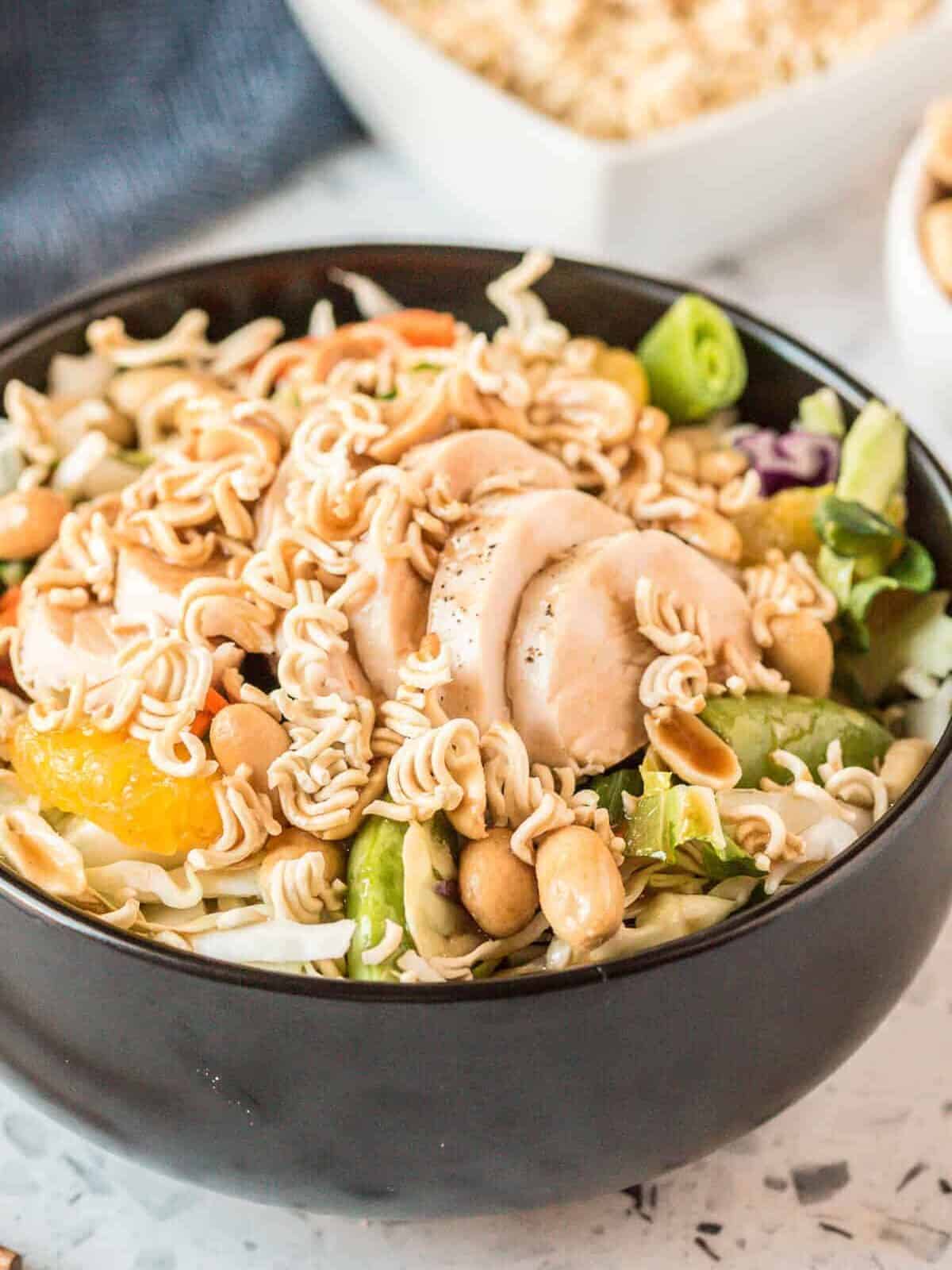 A bowl of Chinese chicken salad topped with crispy ramen noodles.