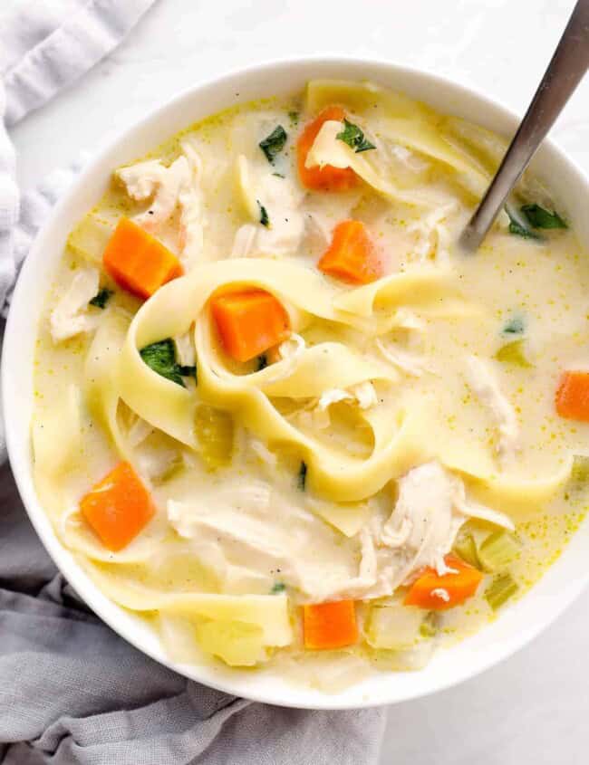 up close bowl of creamy chicken noodle soup with napkin