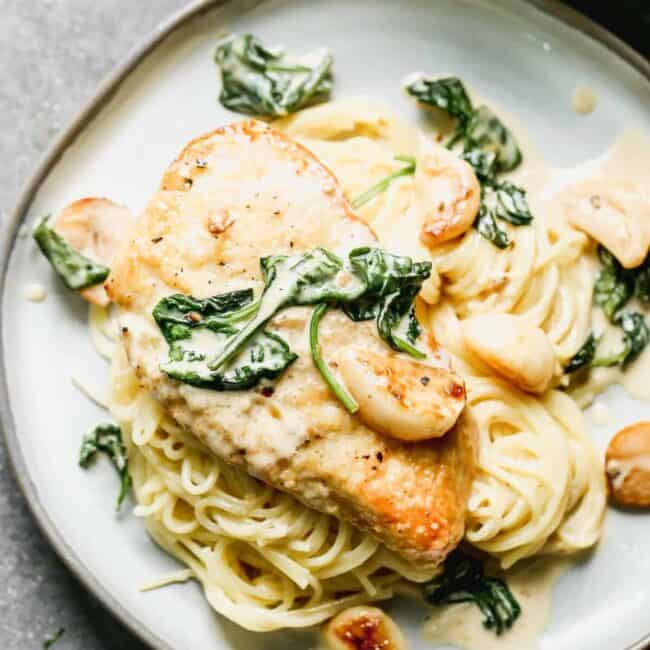 garlic chicken on plate over spaghetti in cream sauce