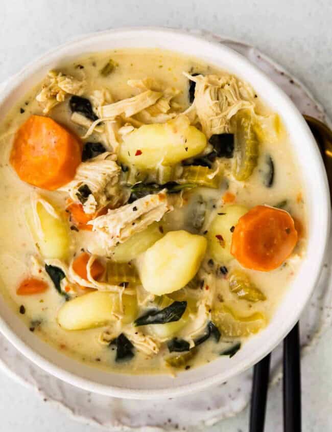 overhead close up of chicken gnocchi soup in a white bowl