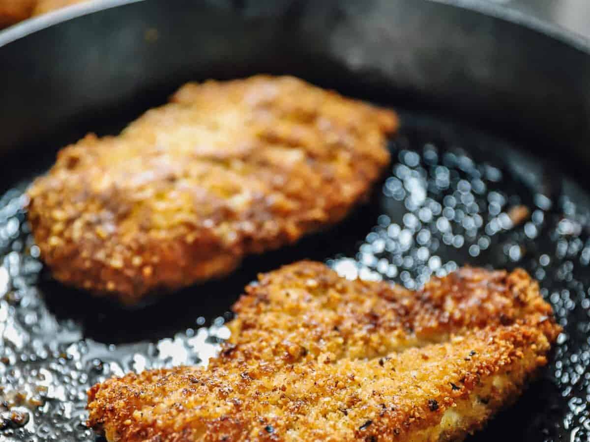 Pan-frying chicken parm in a skillet.
