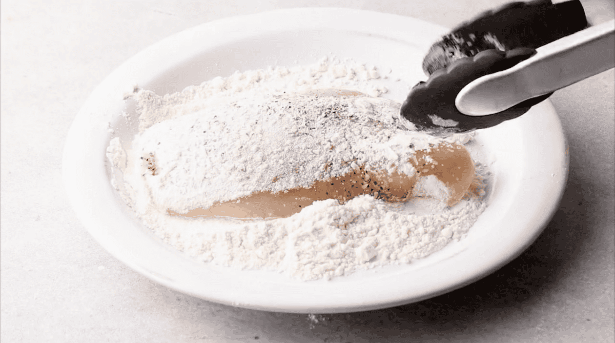 Dredging chicken in flour.