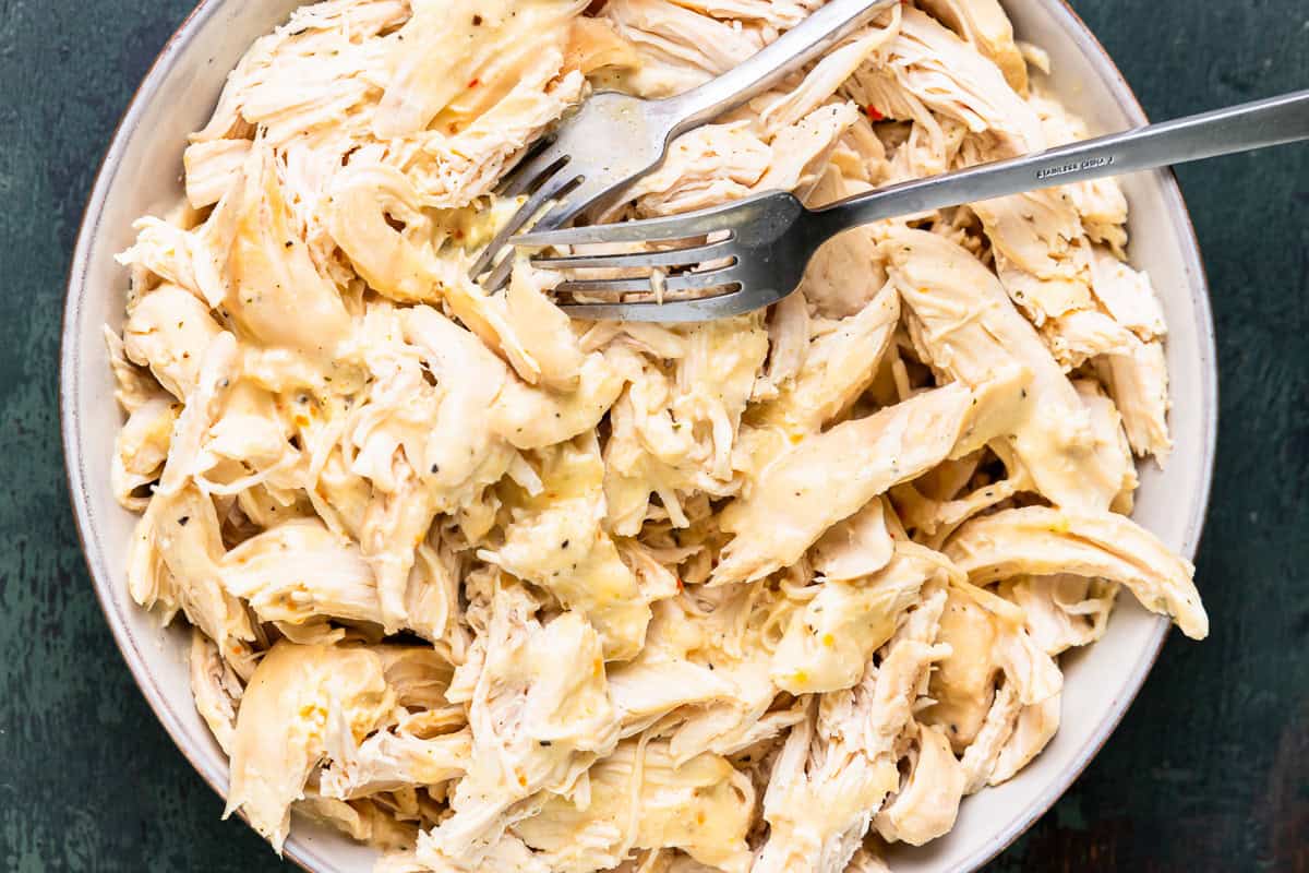 A plate of shredded chicken with two forks.