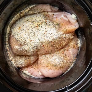 Chicken breasts with Italian dressing seasoning layered in a crock pot.